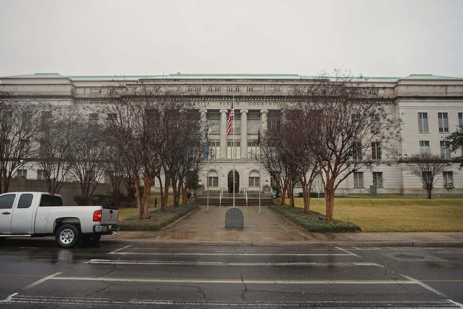 The wide limestone Ouachita Parish Courthouse in Monroe behind a row of crape myrtles