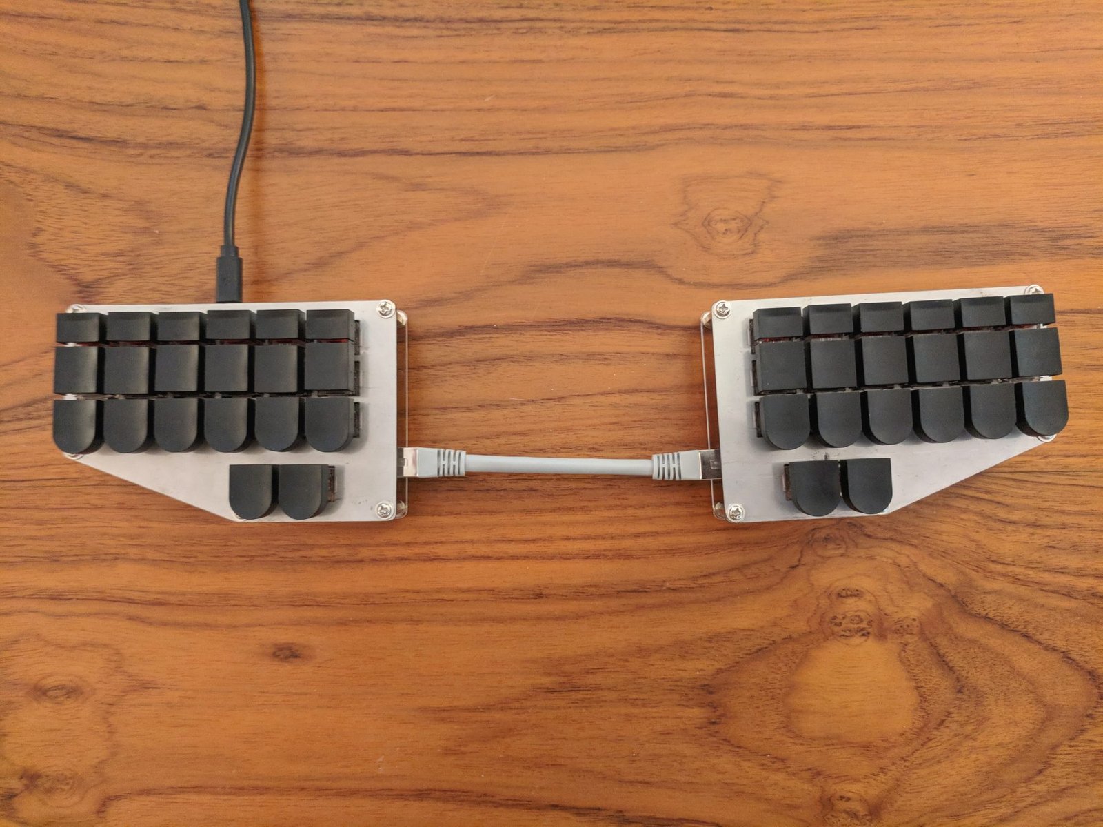A split chorded steno keyboard on a wooden desk
